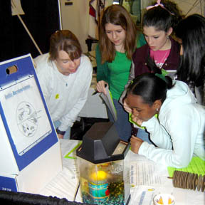 Students interacting with display and SRS employee